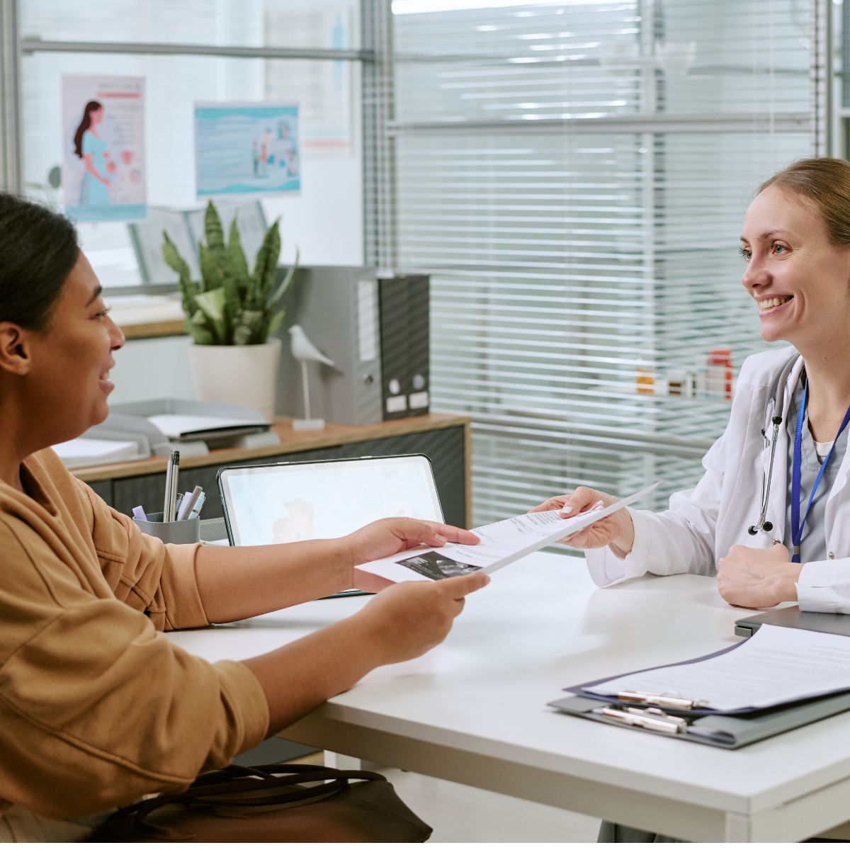Obstetrics female doctor handing paperwork to patient