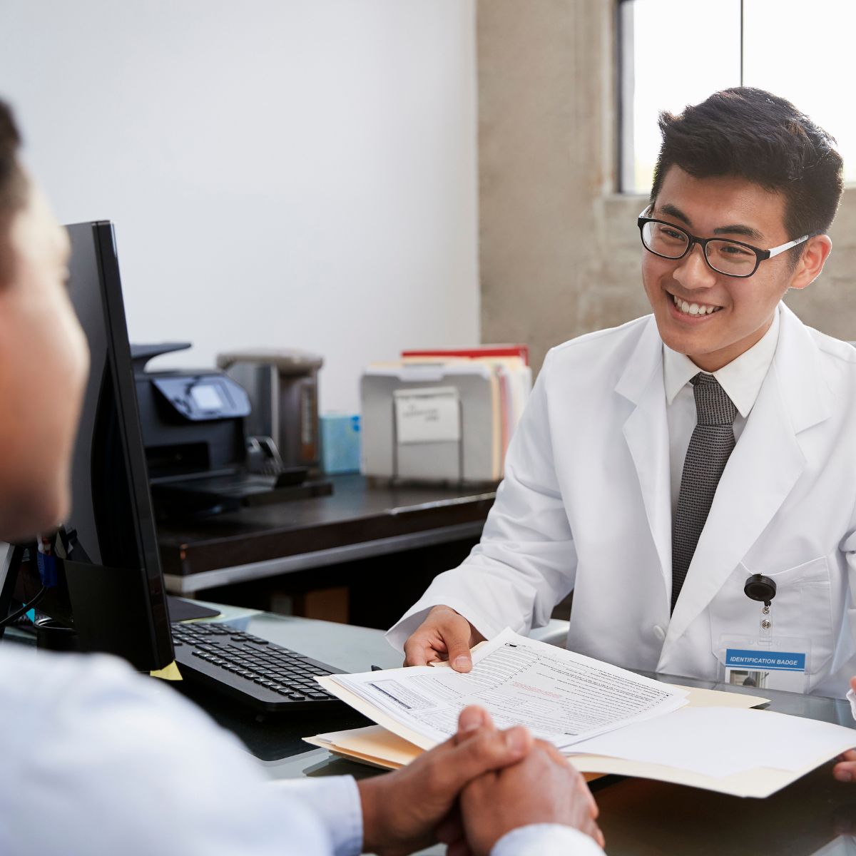 Regulatory and Migration male doctor talking to patient with paperwork
